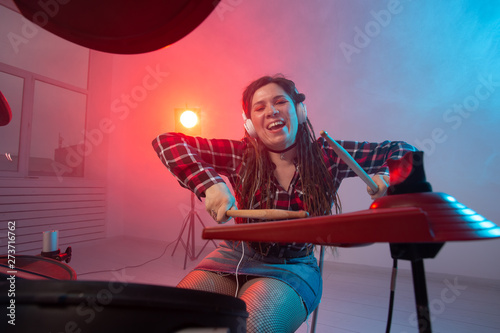 Music, drum and hobby concept - young woman playing the electronic drum set at the club © satura_