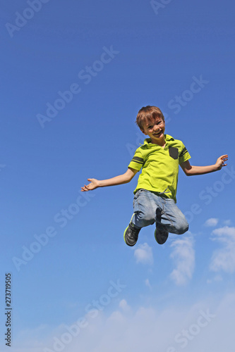 Junge springt in die Luft, im Hintergrund blauer Himmel
