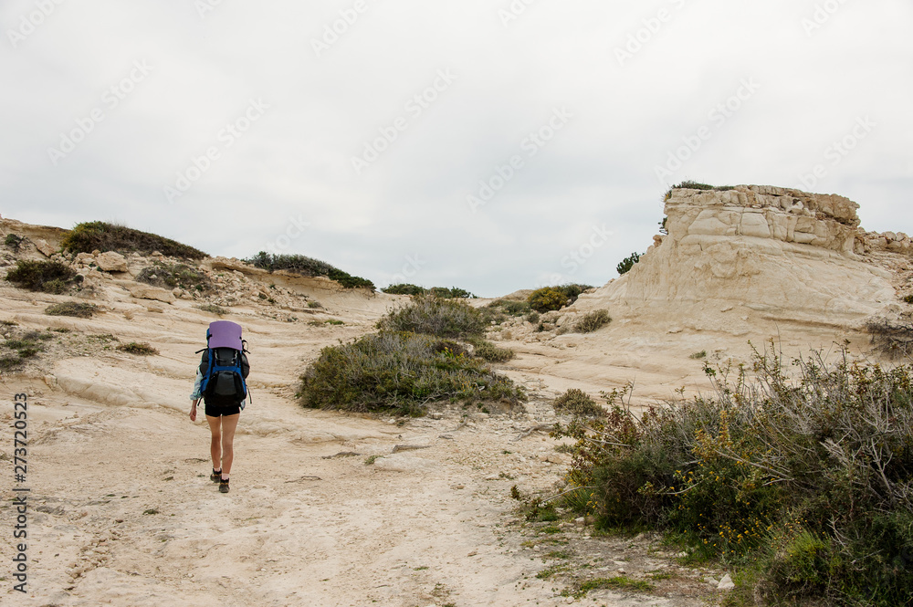Girl walking on the rocks with hiking backpack