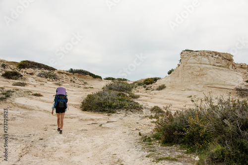 Girl walking on the rocks with hiking backpack