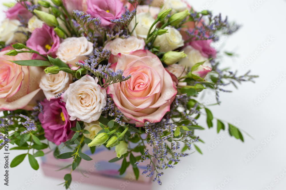 delicate floral arrangement of roses and live decorations in a square cardboard box (primary color - pink) on a light background delicate floral arrangement of roses and live decorations in a square cardboard box (primary color - pink) on a light background