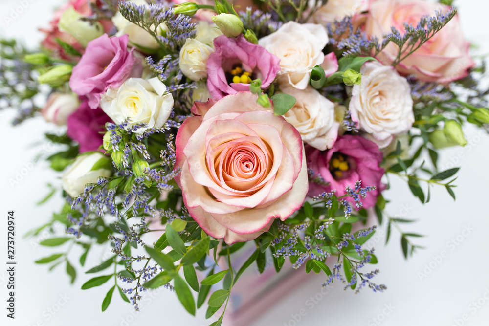 delicate floral arrangement of roses and live decorations in a square cardboard box (primary color - pink) on a light background