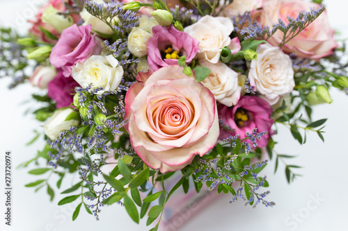 delicate floral arrangement of roses and live decorations in a square cardboard box (primary color - pink) on a light background