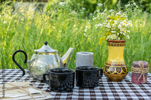 Hygge style summer composition with tea table in the garden.