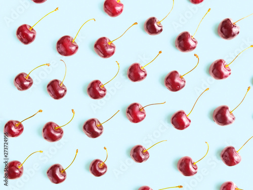 Ripe berries of sweet cherry are on a pale blue background. Flat lay, top view minimal composition.