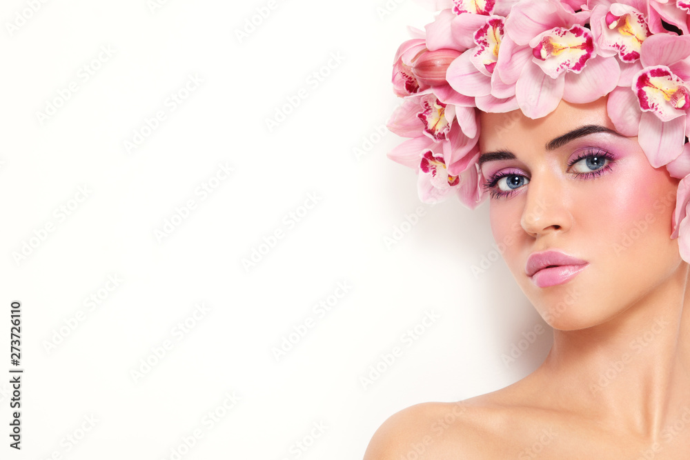 Young beautiful tanned sexy woman with fancy make-up and pink orchids in her hair, copy space