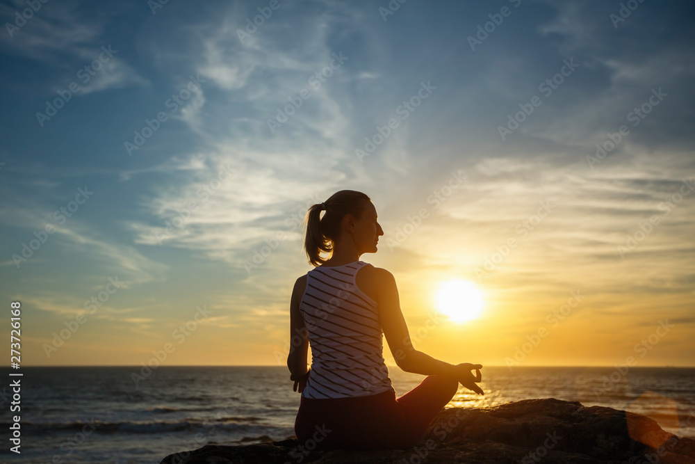 Silhouette meditation girl on the background of the sea and sunset. Yoga and healthy lifestyle...