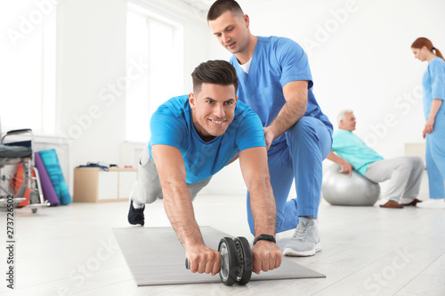 Professional physiotherapist working with male patient in rehabilitation center