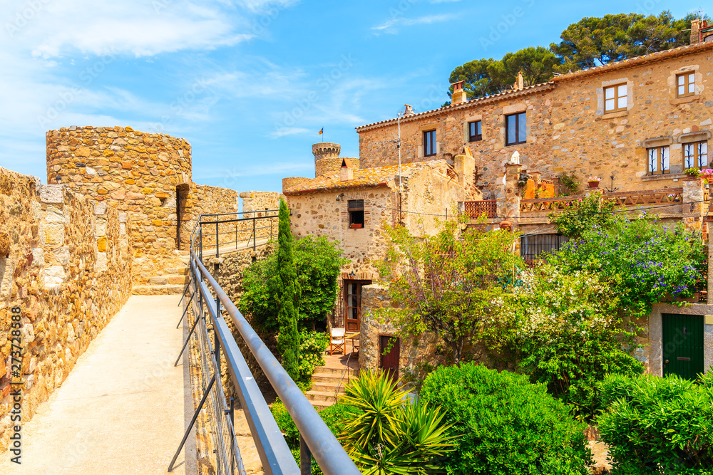 Green tropical plants and stone houses in old town of Tossa de Mar, Costa Brava, Spain