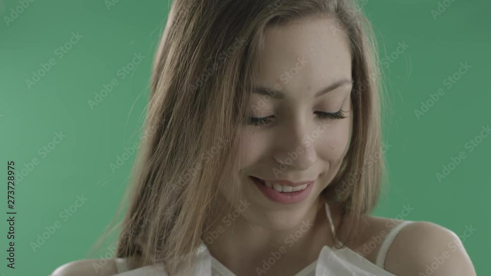 Shy attractive woman giggles against green background Shy attractive woman giggles against green background
