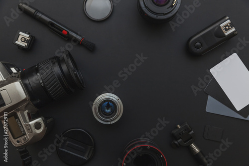 Photographer workplace with dslr camera system, camera cleaning kit, lens and camera accessory on dark black table background. Hobby travel photography concept. Flat lay top view copy space