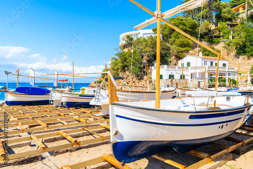 Wallpaper Mural Traditional white and blue colour fishing boat on Sa Riera beach with sea and village houses in background, Costa Brava, Spain Torontodigital.ca
