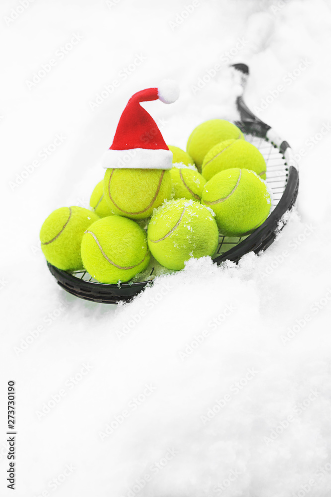 Tennis winter concept with tennis balls and racket on white snow, isolated.  Top view, copy space.