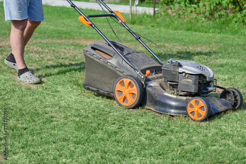 Man is using lawn mower on his countryside yard.