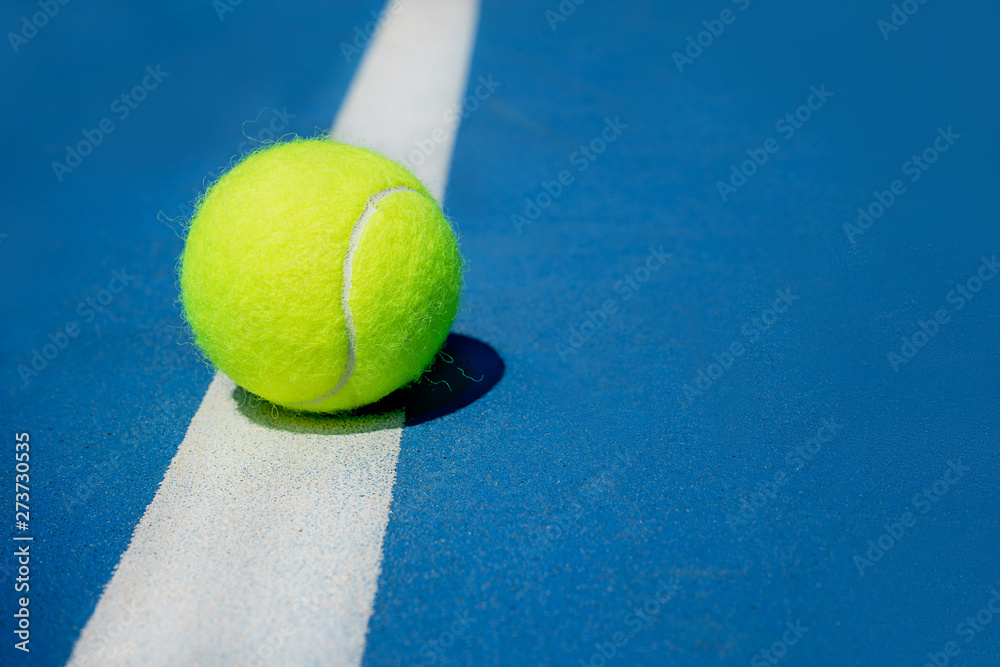 Summer sport concept with tennis ball on white line on hard tennis court. Flat lay, top view, copy space, close up. Blue and green.