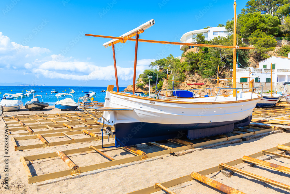 Φωτογραφία Traditional fishing boat on Sa Riera beach with sea and village houses in backgr