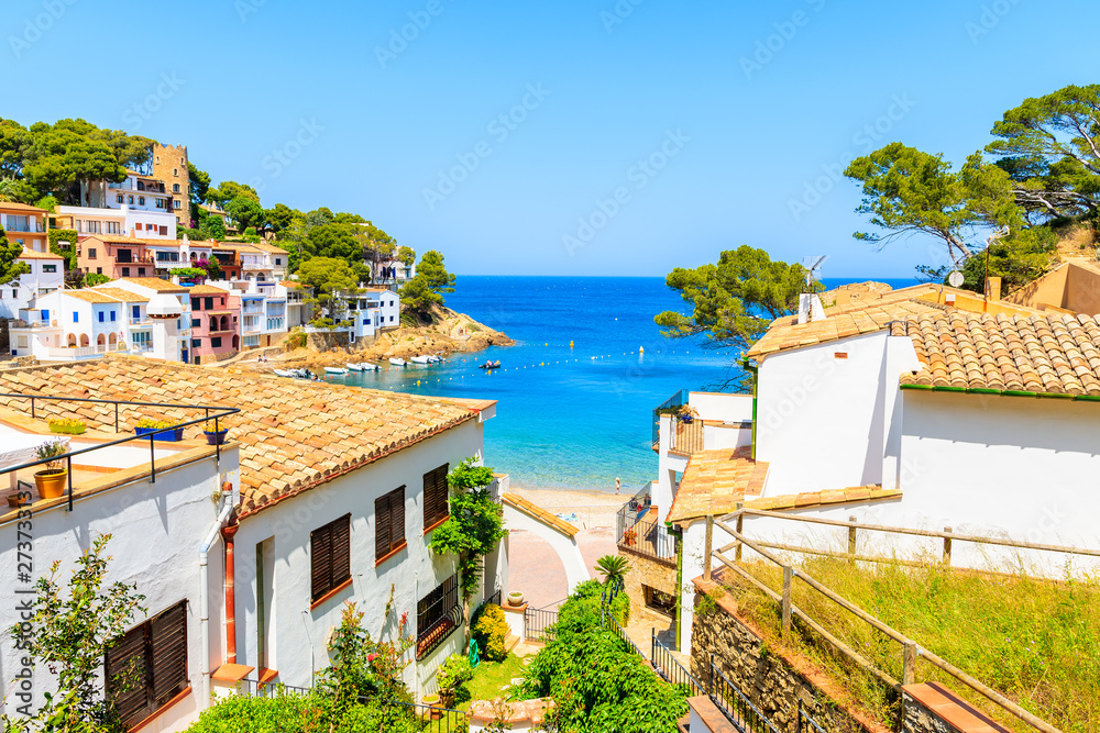 White houses with orange tile roofs and steps to beach in Sa Tuna coastal fishing village, Costa Brava, Spain