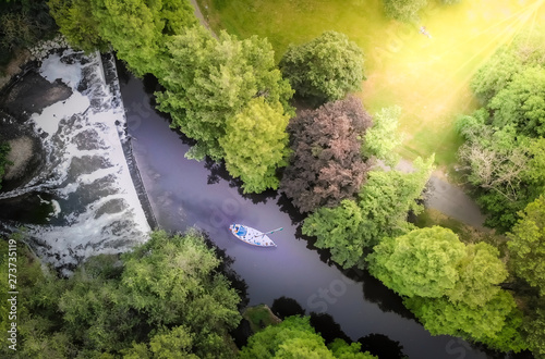 Aerial view of a nice green forest with a beautiful waterfall and a boat sailing in the river