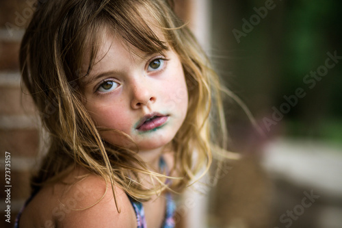 5 year old girl with blue around mouth from candy looking into distanc photo