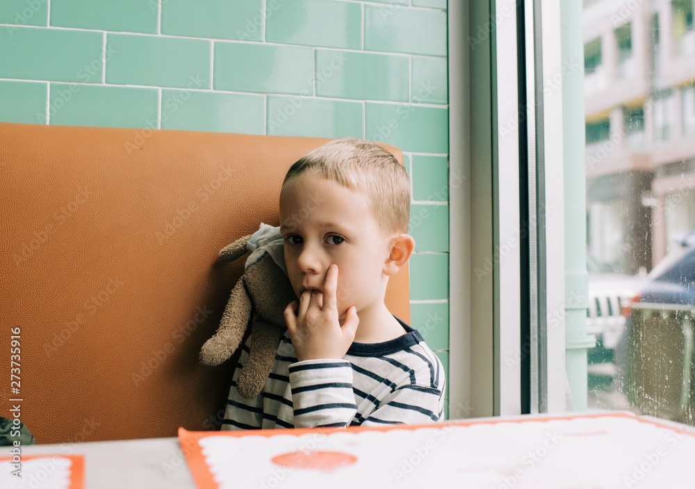 young boy looking at the camera with fingers in mouth with his bear young boy looking at the camera with fingers in mouth with his bear