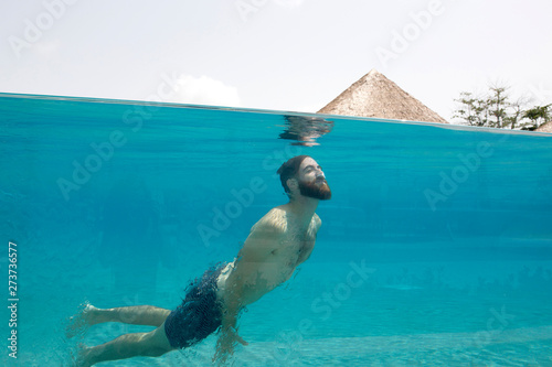 Man swims in glass pool on vacation photo