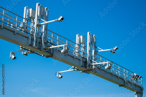 Overhead highway speed cameras on an arch of metal. Traffic cameras over the motorway on a blue sky background.