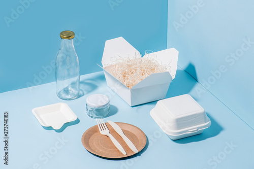 Recyclable paper tableware, cornstarch cutlery, glassware over blue photo