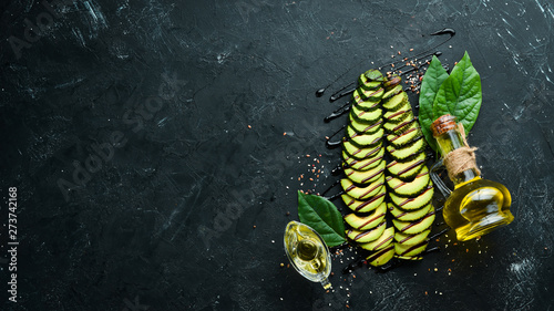 Sliced avocado and spices on a black background. Rustic style. Top view. Free space for your text.