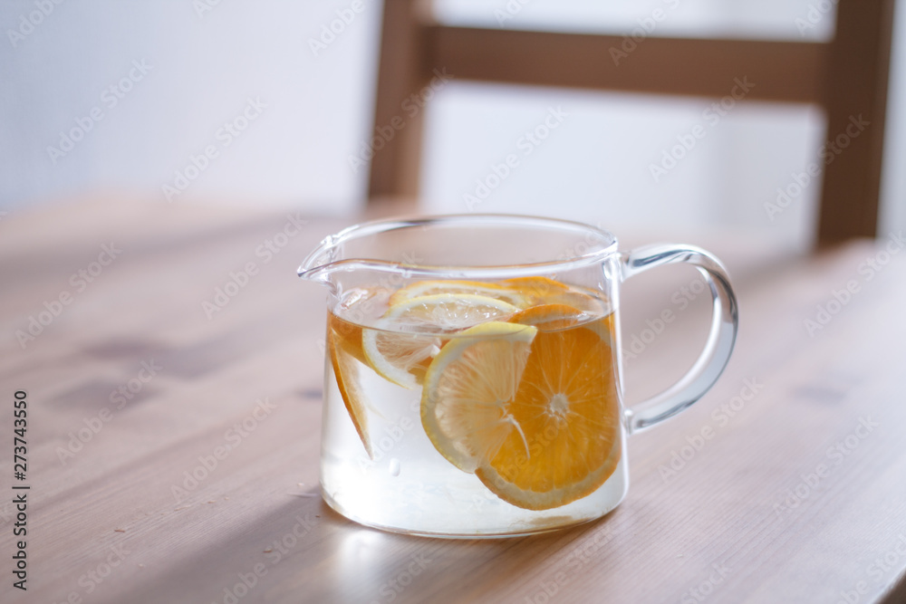 pitcher with lemonade and water sliced oranges and lemon on wooden table and coral and blue table background close up with blurred background pitcher with lemonade and water sliced oranges and lemon on wooden table and coral and blue table background close up with blurred background