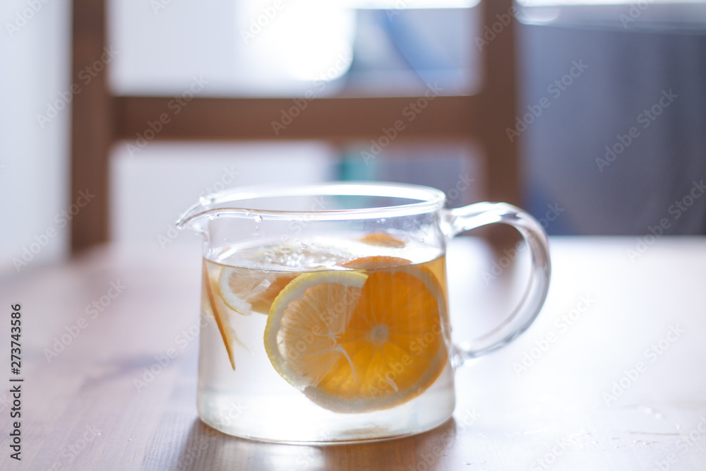 pitcher with lemonade and water sliced oranges and lemon on wooden table and coral and blue table background close up with blurred background pitcher with lemonade and water sliced oranges and lemon on wooden table and coral and blue table background close up with blurred background