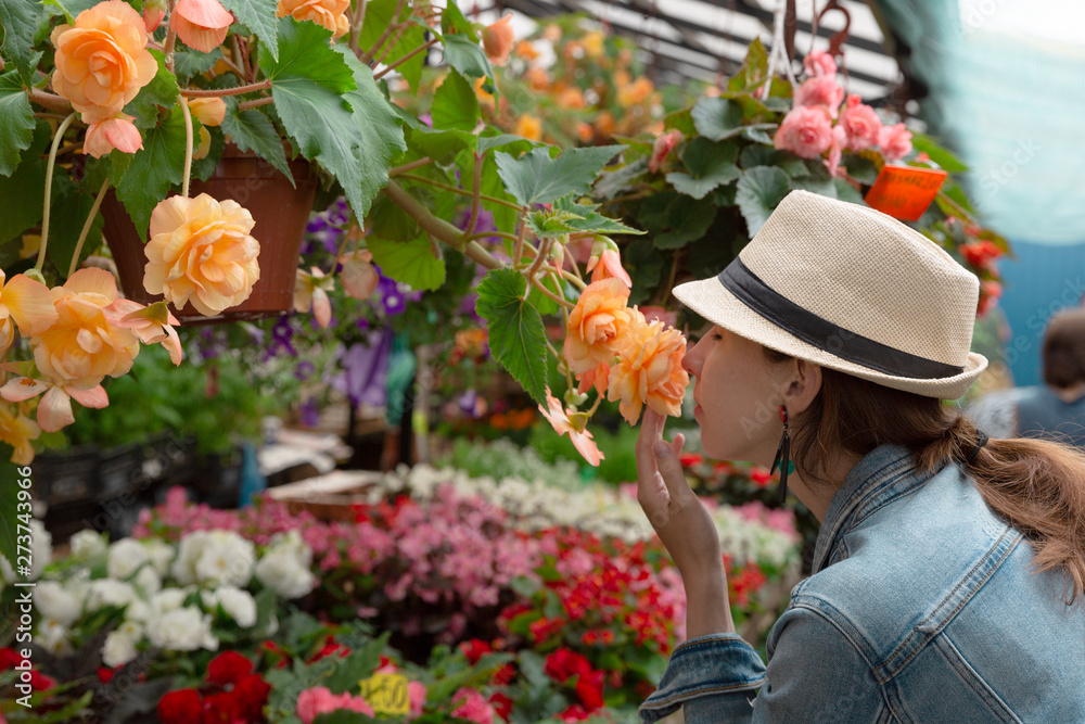  Young woman shopping in an outdoors fresh urban flowers market, buying and picking from a large variety of colorful floral bouquets during a sunny day in the city