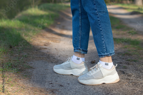 female legs in white sneakers