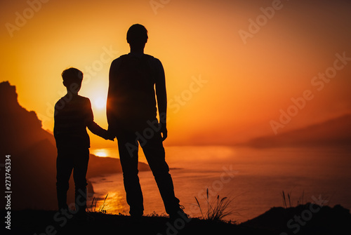 silhouette of father and son holding hands in sunset nature