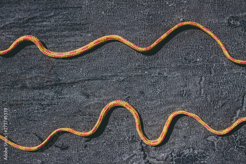 Bright orange rope on a texured roofing felt surface with many small cracks photo