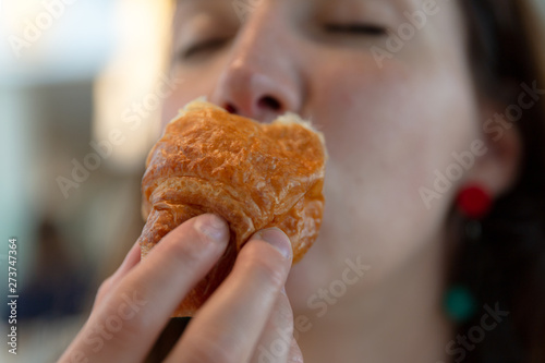 Young woman eating croissant  pleasure  guilt free eating