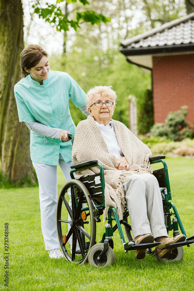 Young female nurse with disabled in the garden Young female nurse with disabled in the garden