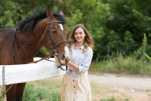 Portrait of young pretty cheerful woman with horse at summer 