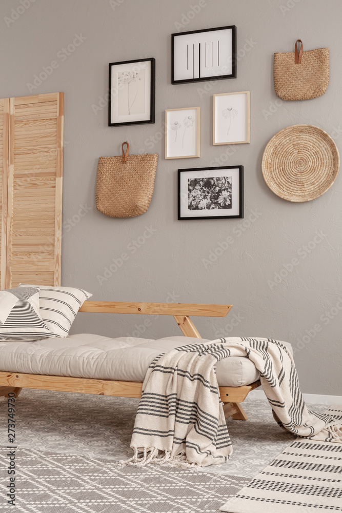 Gallery of black and white posters and wicker accessories on beige wall of Scandinavian living room