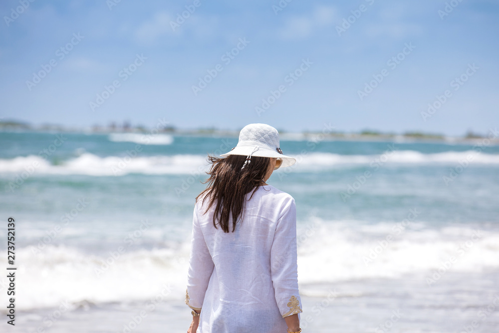 Woman walking at an empty paradisiac tropical beach in a beautiful sunny day