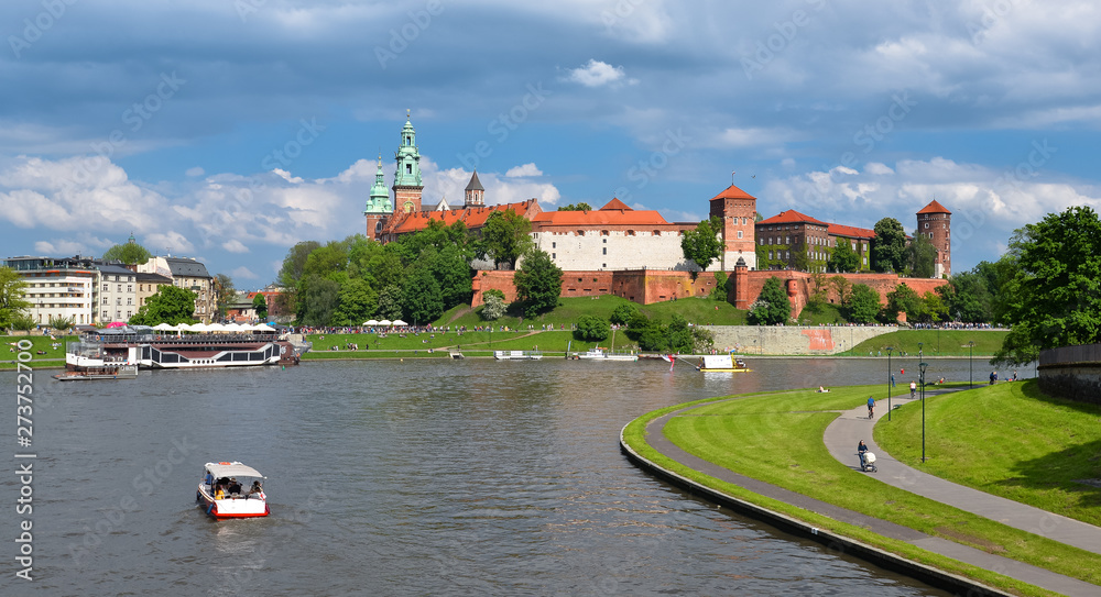 Spring view on Wawel Castle, Vistula River, spring park, bicycle lane and walking tourists Spring view on Wawel Castle, Vistula River, spring park, bicycle lane and walking tourists