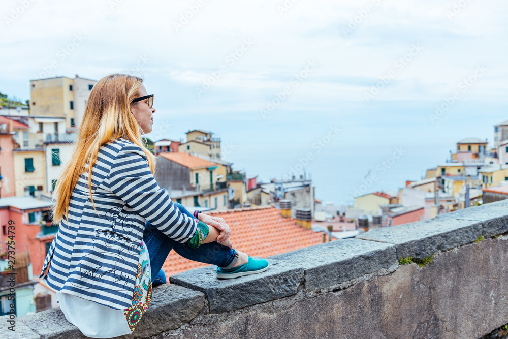 Beautiful young woman enjoying the view of Manarola in the UNESCO World Heritage Site Cinque Terre, Liguria, Italy