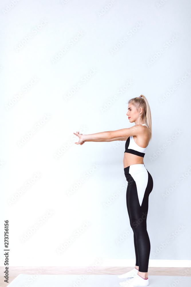 Fitness woman doing squats in black-white sportswear.
