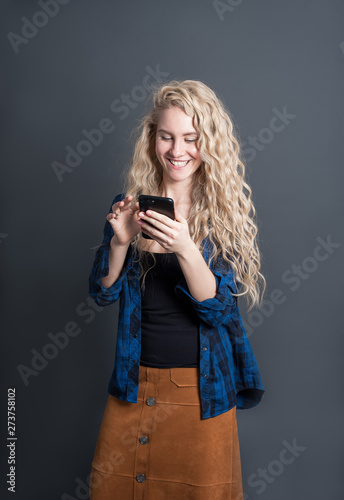  young woman with a mobile phone is smiling. on dark studio background 