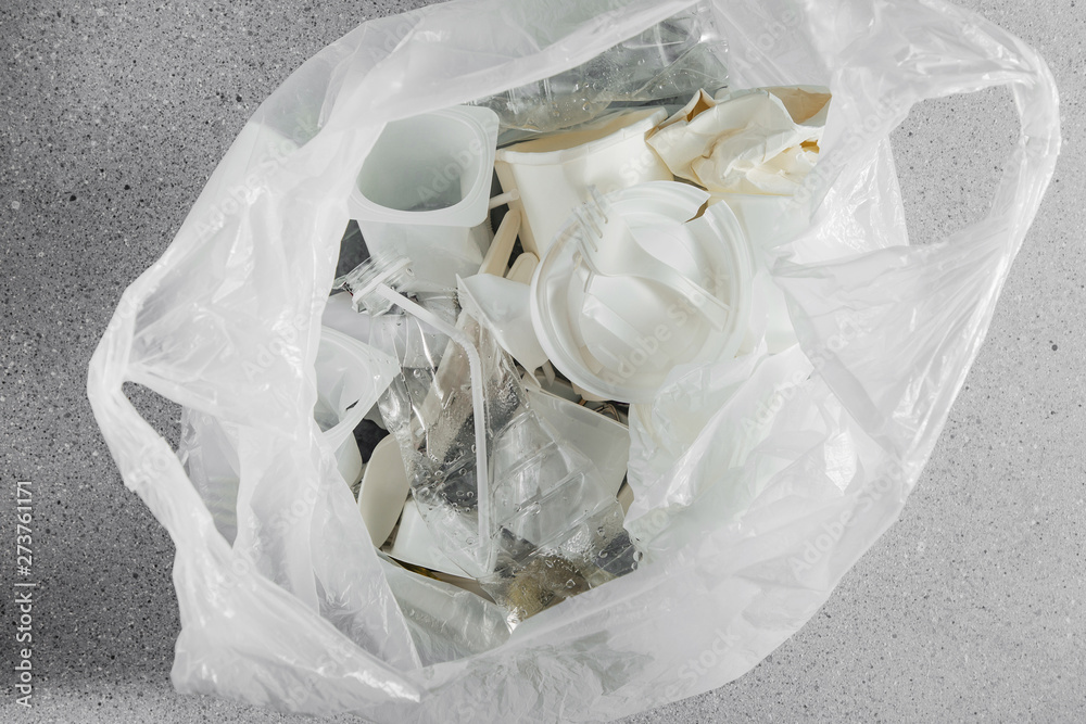 White single use plastic in plastic bag. Closeup. Concept of Recycling plastic and ecology. Flat lay, top view. White single use plastic in plastic bag. Closeup. Concept of Recycling plastic and ecology. Flat lay, top view.