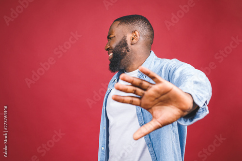Slika na platnu Portrait of African American male holding hand in stop sign, warning and preventing you from something bad, looking at the camera with worried expression