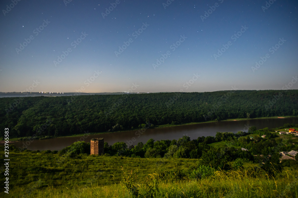 Obraz premium Ruined old castle tower at night on the river bank