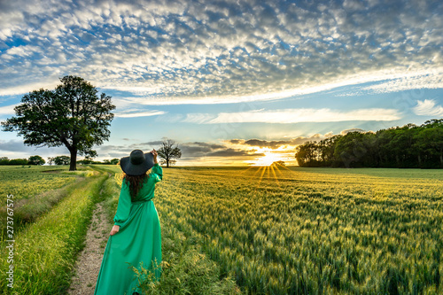 Wallpaper Mural Portrait of a beautiful young woman in green dress on meadow watching the sunset enjoying nature Torontodigital.ca
