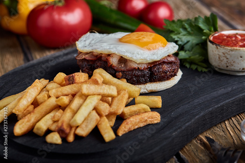 Beef steak with egg and salad from greens and vegetables. Wooden background, table setting, fine dining