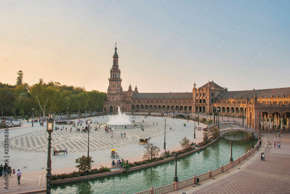 Wide view of the Plaza de España at sunset with tourists visiting it