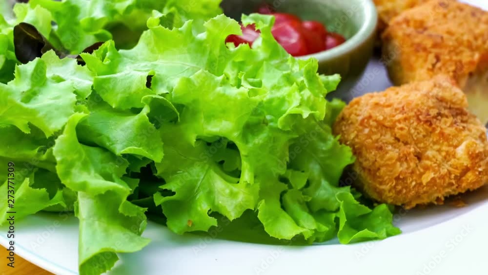 Delicious cylindrical croquettes and fresh vegetables in a white plate turning on a wooden board Delicious cylindrical croquettes and fresh vegetables in a white plate turning on a wooden board